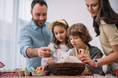 Genç aile ile masaya oturan tavşan Paskalya tatil hazırlanma
