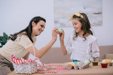 mutlu genç anne ve kızı dokunarak üstünde Paskalya yortusu yumurta yapıyor