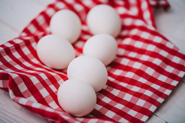 white chicken eggs on red plaid napkin