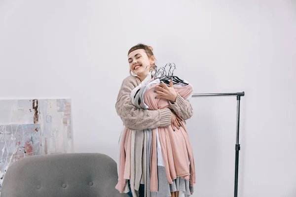 Glückliches Mädchen hält Kleiderstapel auf Kleiderbügeln — Stockfoto