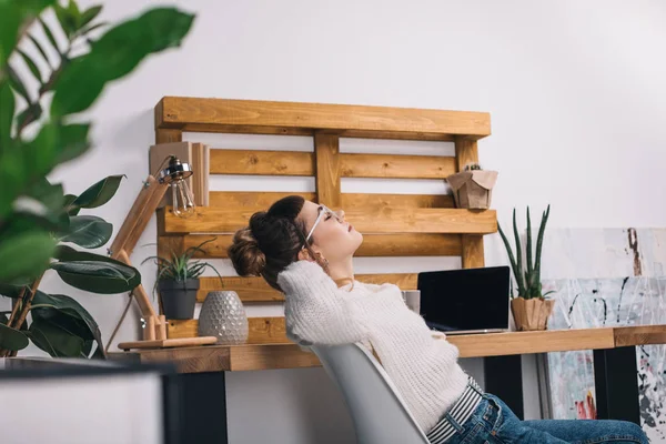 Seitenansicht eines Mädchens, das sich im Büro auf einem Stuhl dehnt — Stockfoto