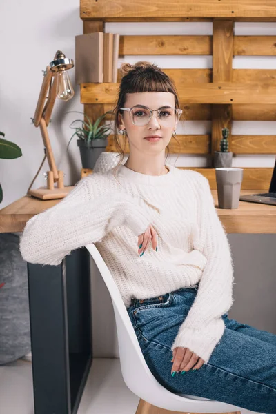 Girl sitting on chair in office and looking at camera — Stock Photo