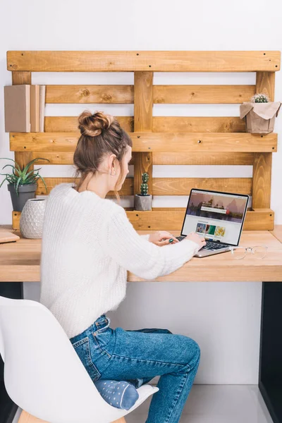 Girl sitting at table with laptop with loaded shutterstock page — Stock Photo
