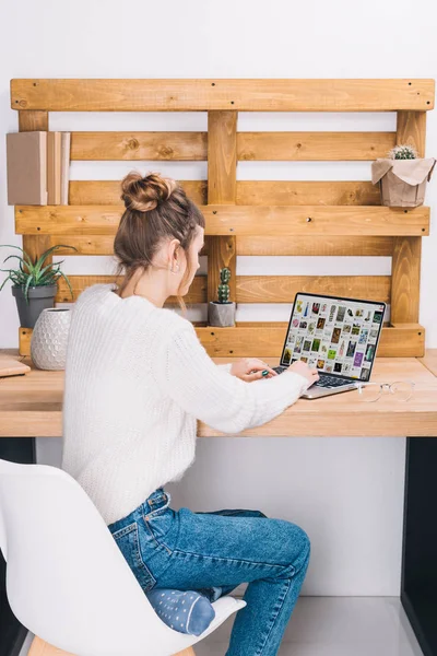 Girl sitting at table with laptop with loaded pinterest page — Stock Photo