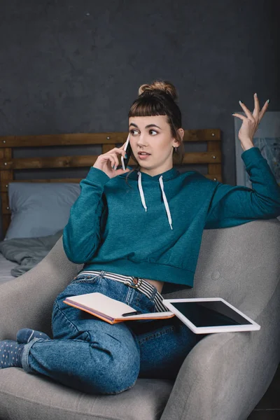 Irritated girl working from home and talking by smartphone — Stock Photo