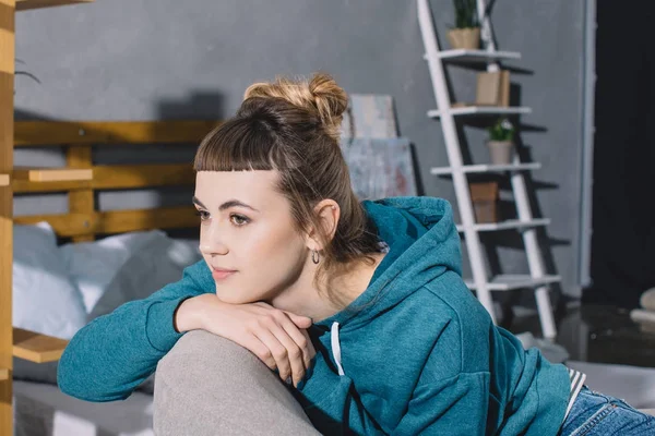 Chica sentada en sillón en el dormitorio y mirando hacia otro lado - foto de stock