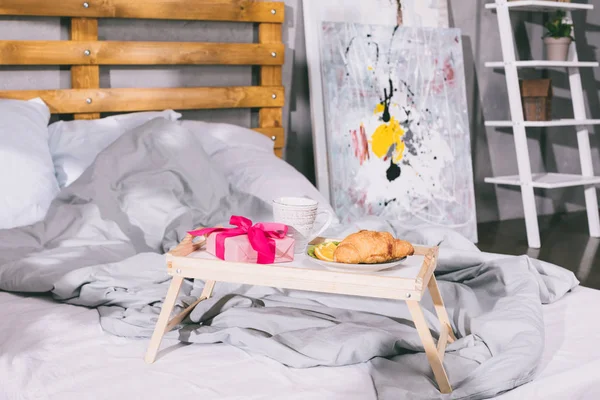 Tablett mit Frühstück und Geschenkbox auf Decke auf dem Bett — Stockfoto