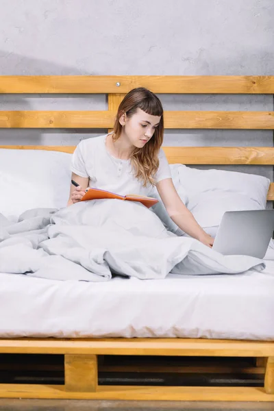 Fille étudiant dans le lit le matin et en utilisant un ordinateur portable — Photo de stock