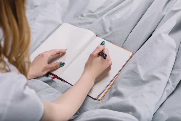 Imagem cortada de menina escrevendo algo para notebook — Fotografia de Stock