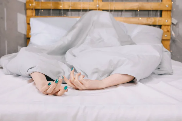 Abgeschnittenes Bild eines Mädchens mit Maniküre, das unter einer Decke auf dem Bett liegt — Stockfoto