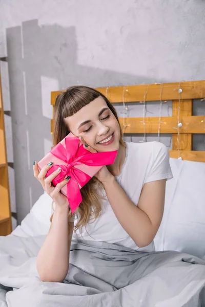 Chica sonriente tocando caja de regalo con cara - foto de stock