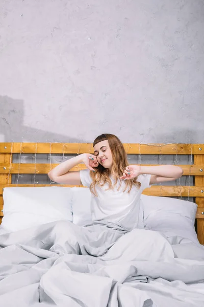 Glückliches Mädchen dehnt sich morgens im Bett — Stockfoto