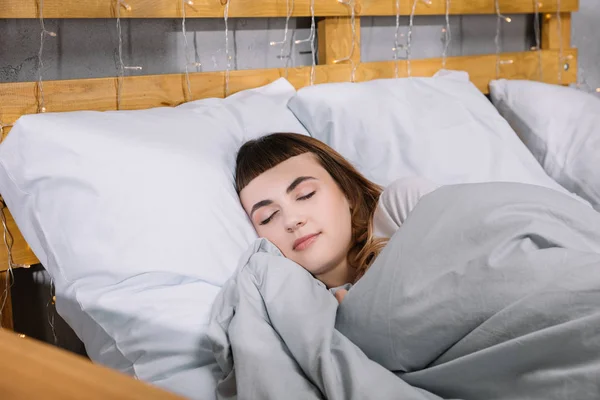 Menina dormindo em almofadas brancas no quarto — Fotografia de Stock