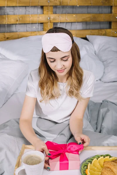 Girl opening present box in bed in morning — Stock Photo