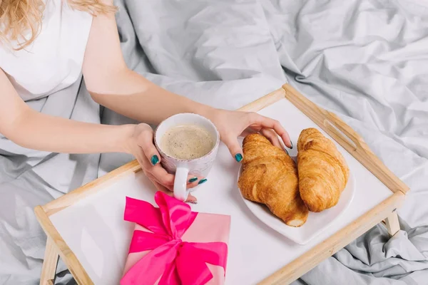 Cropped image of girl taking croissant from plate — Stock Photo