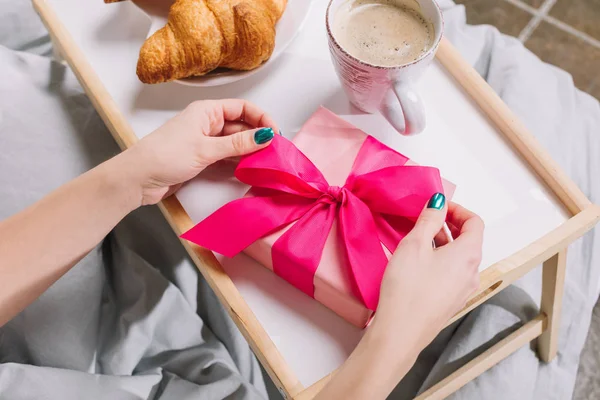 Imagen recortada de niña apertura caja de regalo en bandeja - foto de stock