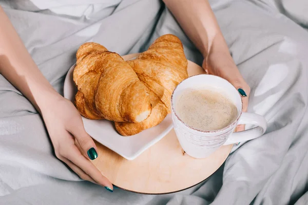 Cropped image of girl holding tray with croissants and coffee — Stock Photo