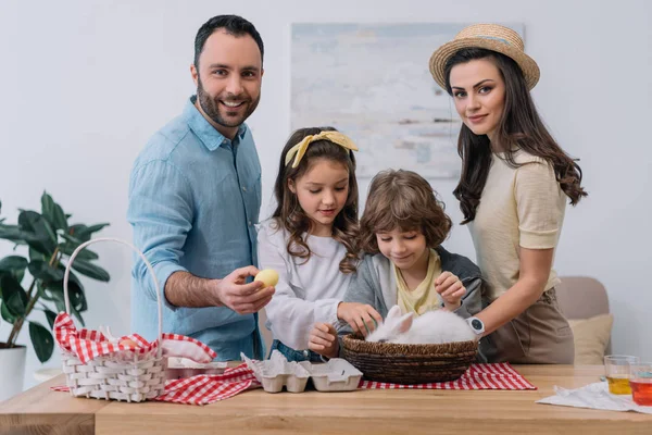 Jeune famille avec œufs colorés et lapin se préparant pour Pâques — Photo de stock