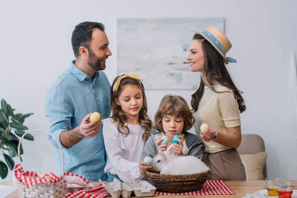 Familia joven con coloridos huevos de Pascua preparándose para la Pascua - foto de stock