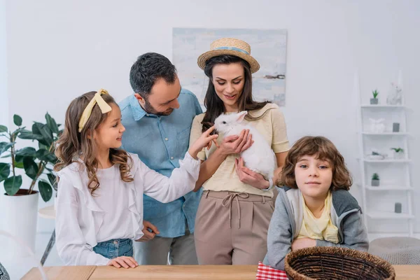 Joven familia con blanco adorable conejito en casa - foto de stock