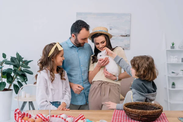 Feliz familia joven con hermoso conejito blanco en casa - foto de stock