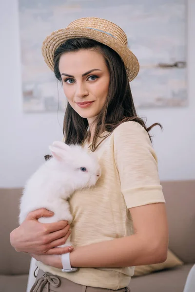 Joven elegante mujer en sombrero celebración lindo conejo blanco - foto de stock