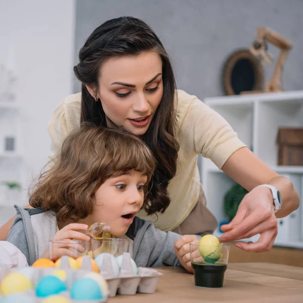 Son helping mother with eggs painting for easter holiday — Stock Photo