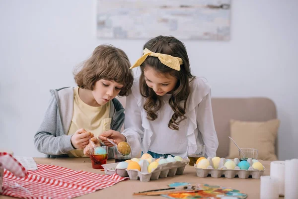 Adorables niños pintando huevos de Pascua juntos - foto de stock