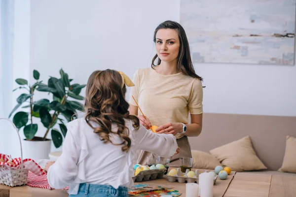 Young mother and daughter painting easter eggs at home — Stock Photo