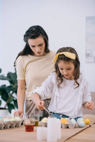 Mother and little daughter painting easter eggs together — Stock Photo