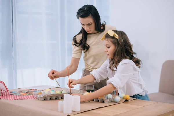 Mother and adorable daughter painting easter eggs together — Stock Photo