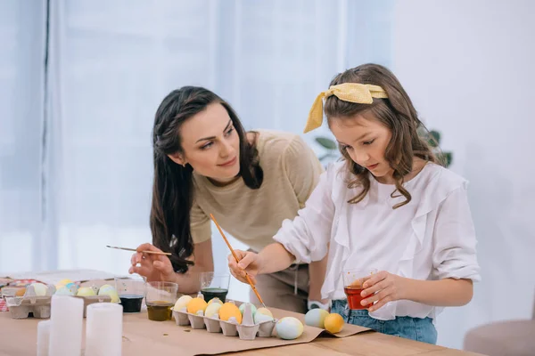 Jeune mère et fille peinture Pâques oeufs ensemble — Photo de stock