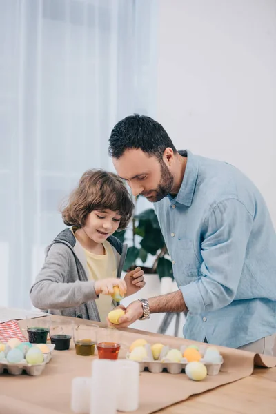 Concentrated young father and son painting easter eggs — Stock Photo