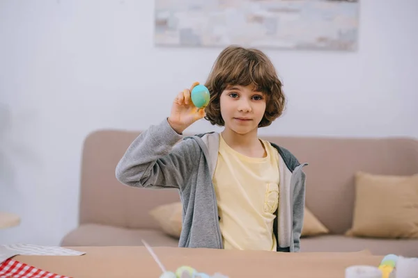 Счастливый ребенок показывает свежеокрашенное пасхальное яйцо в камеру — стоковое фото
