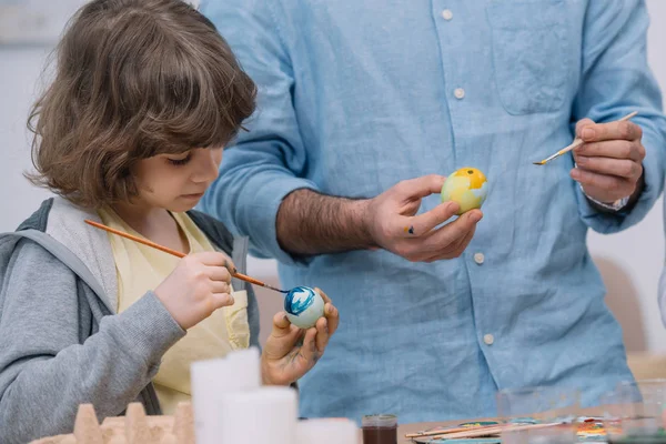 Adorable little child painting easter eggs with father — Stock Photo