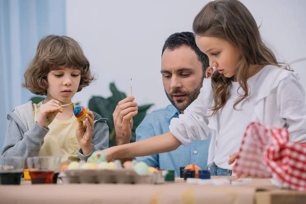 Handsome young father painting easter eggs with kids — Stock Photo