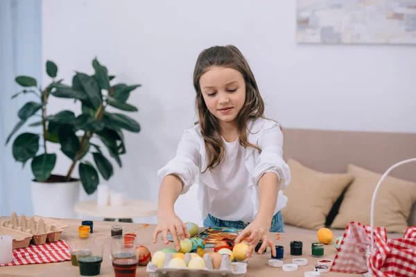 Happy little child painting easter eggs — Stock Photo