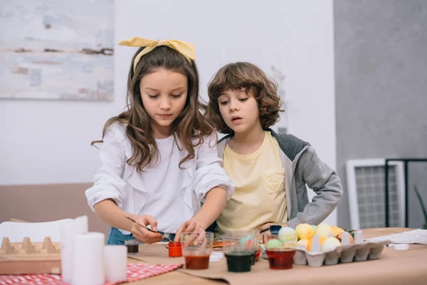 Cute children painting easter eggs together — Stock Photo