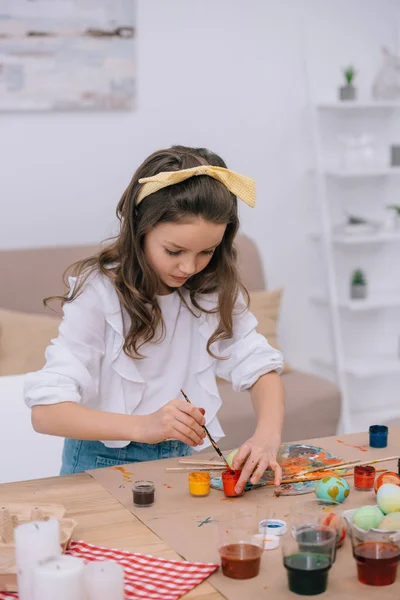 Concentrated little child painting easter eggs — Stock Photo