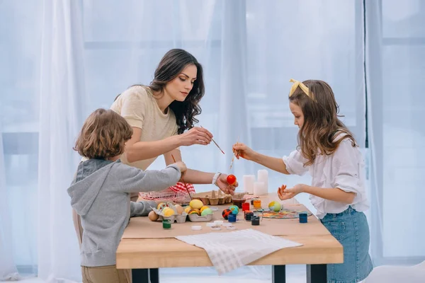 Adorable children painting easter eggs mother at home with mother — Stock Photo