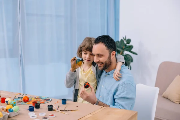 Young smiling father painting easter eggs with son — Stock Photo