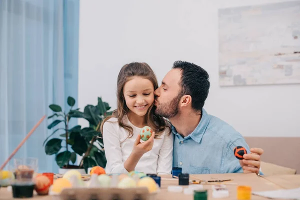 Padre besar hija mientras pintando huevos de Pascua - foto de stock