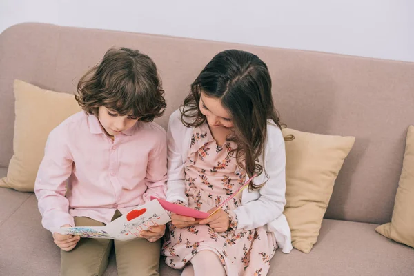 Kinder mit Muttertagsgrüßkarten sitzen zu Hause auf der Couch — Stockfoto