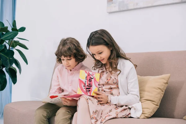 Дети с открытками на день матери сидят дома на диване — стоковое фото