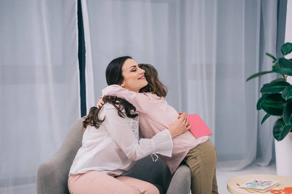 Son embracing mother after giving her greeting card on mothers day — Stock Photo