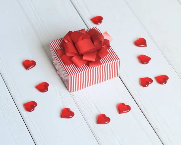 Confezione regalo con fiocco rosso e cuori su sfondo chiaro — Foto Stock