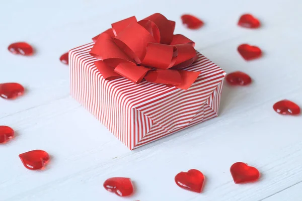 Confezione regalo con fiocco rosso e cuori su sfondo chiaro — Foto Stock