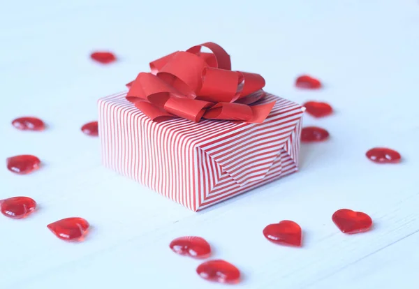Confezione regalo con fiocco rosso e cuori su sfondo chiaro — Foto Stock