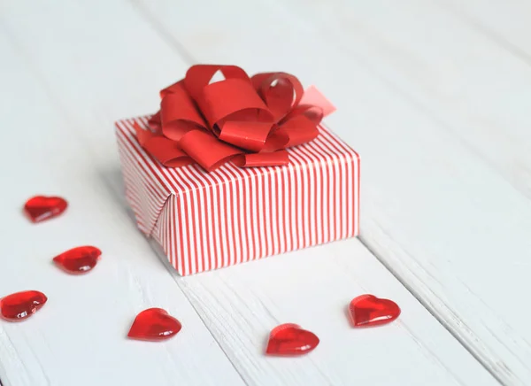 Confezione regalo con fiocco rosso e cuori su sfondo chiaro — Foto Stock