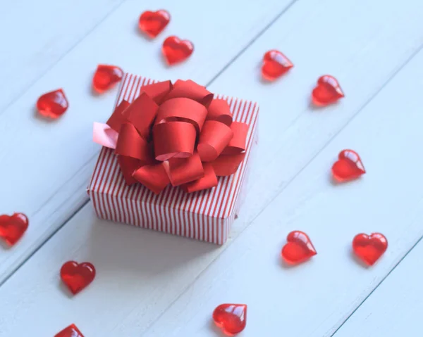 Confezione regalo con fiocco rosso e cuori su sfondo chiaro — Foto Stock